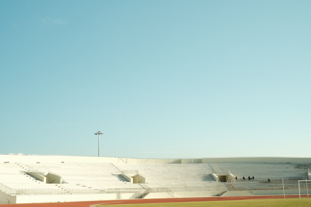 A serene image of empty stadium bleachers with a clear blue sky overhead.