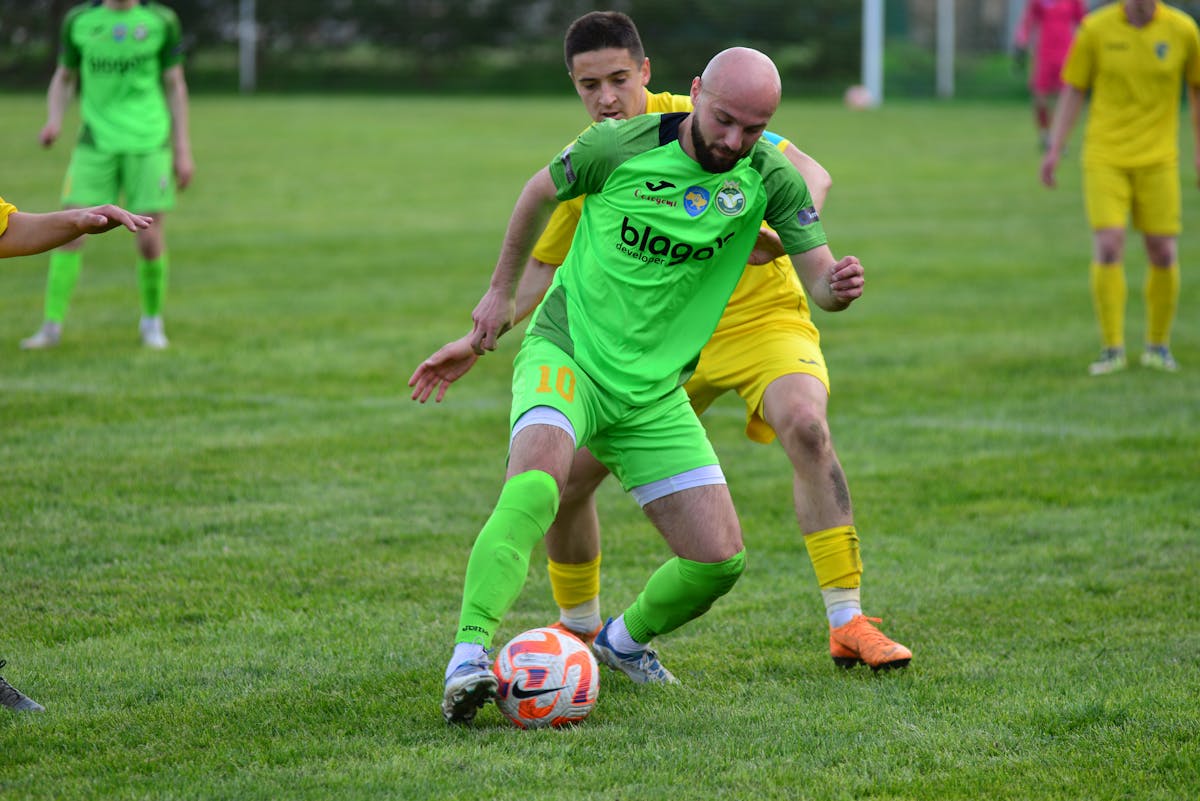 Players in vibrant jerseys compete fiercely in a soccer match on lush green field.