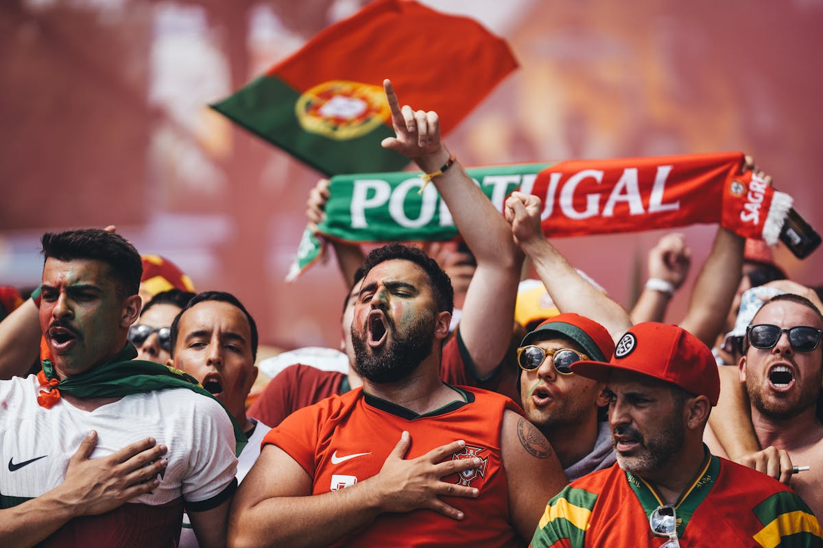 Passionate Portugal football supporters cheering with flags and scarves in vibrant celebration.